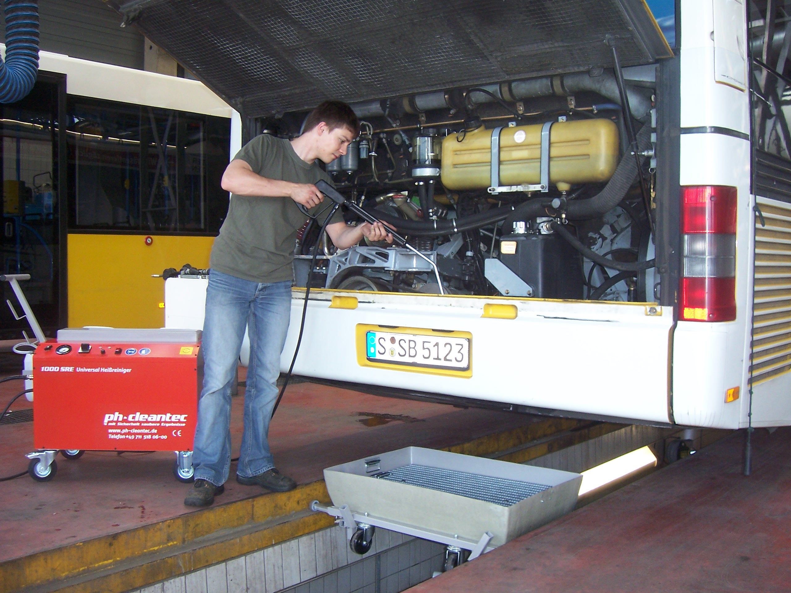 Cleaning the engine compartment of a public transport bus, above the pit, at the pit, dirt water collector