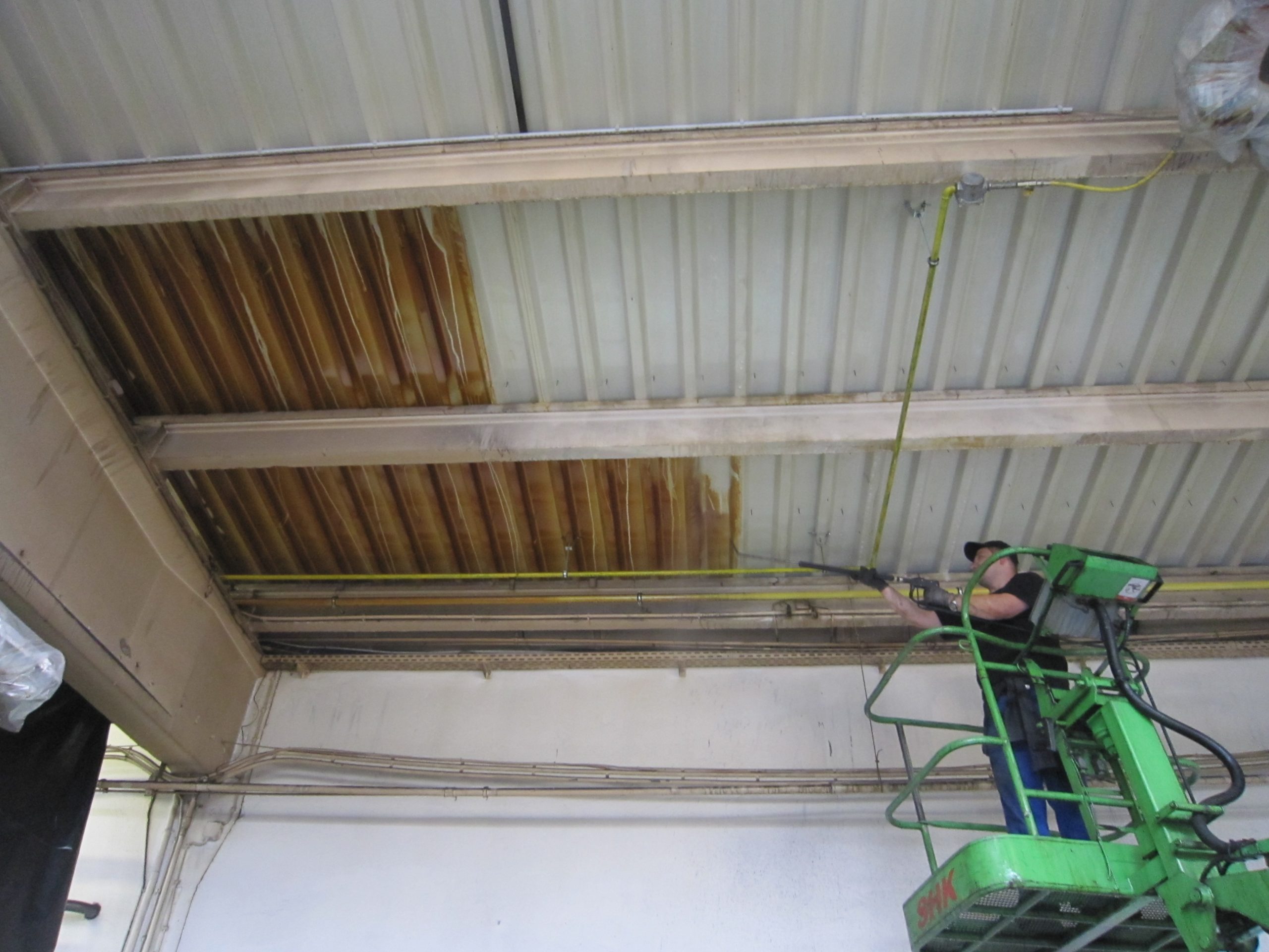 Hallendeckenreinigung 1 Reinigen, Hallendecke mit Verschmutzungen, Hallendecke verschmutzt, Ölnebel, Hubsteiger, Produktionshalle, Werkhalle, keine Tröpfchenwolken